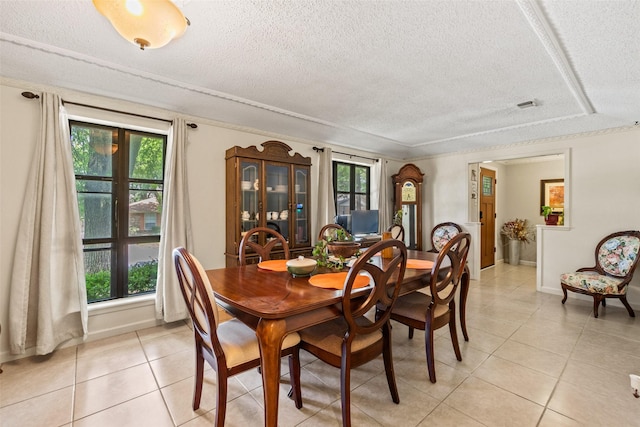 dining room with a textured ceiling, healthy amount of natural light, light tile patterned flooring, and baseboards