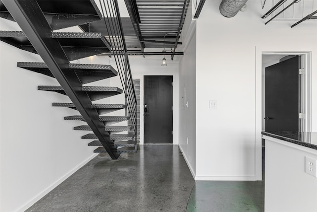 staircase featuring baseboards and concrete floors