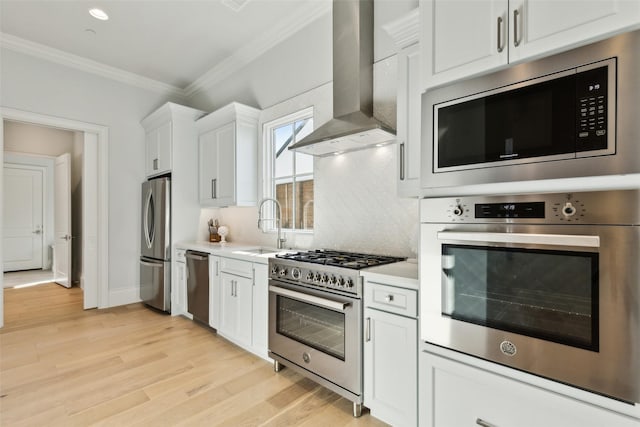 kitchen with wall chimney exhaust hood, appliances with stainless steel finishes, a sink, ornamental molding, and light countertops