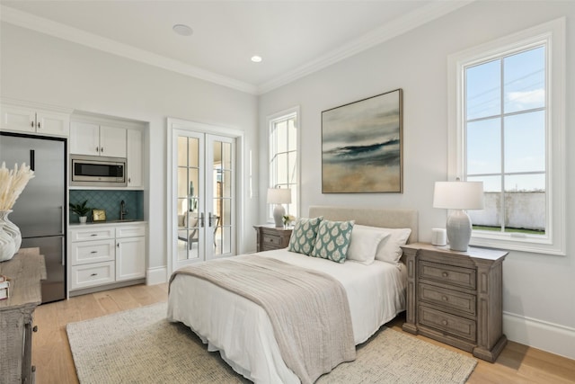 bedroom with stainless steel fridge, ornamental molding, light wood-style floors, baseboards, and a sink