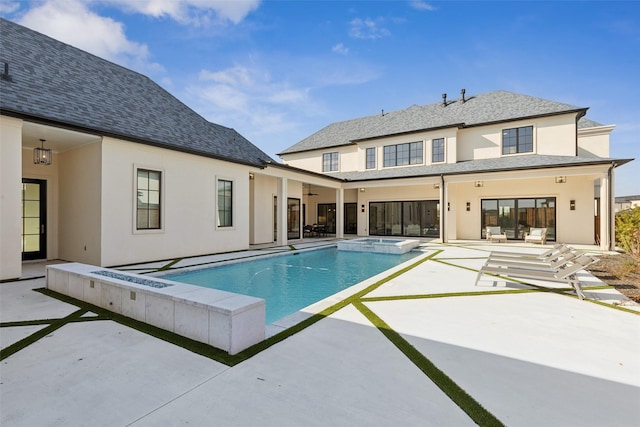 rear view of house featuring a patio, stucco siding, ceiling fan, and a pool with connected hot tub