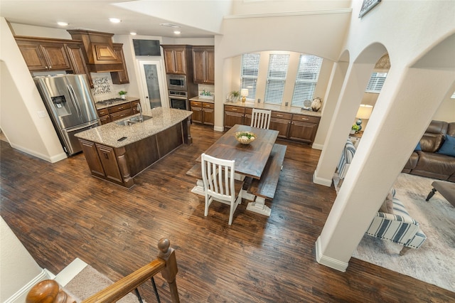 1519 Eminence Ln, Saint Paul, TX 75098 - kitchen featuring stainless steel appliances, a sink, arched walkways, a center island with sink, and dark wood-style floors