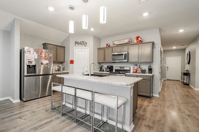 kitchen featuring stainless steel appliances, light wood-style floors, a breakfast bar, an island with sink, and recessed lighting
