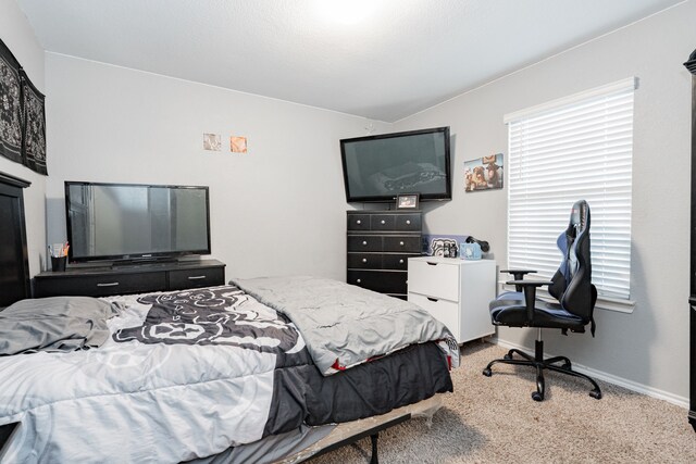 carpeted bedroom featuring baseboards and an office area