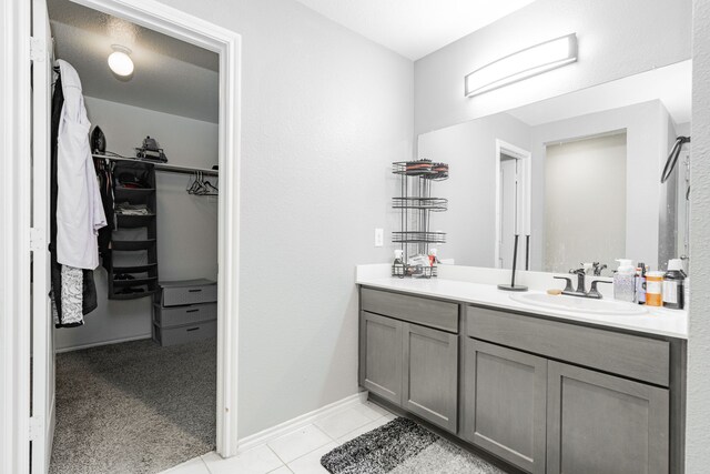 full bath featuring a spacious closet, vanity, tile patterned floors, and baseboards