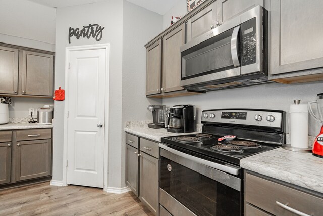 kitchen with stainless steel appliances, light wood-type flooring, and light countertops