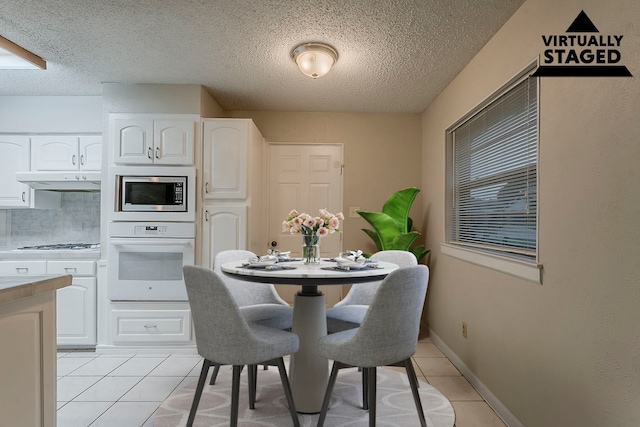 1600 Lagoona Ln, Edgecliff Village, TX 76134 - dining area featuring light tile patterned floors, a textured ceiling, and baseboards