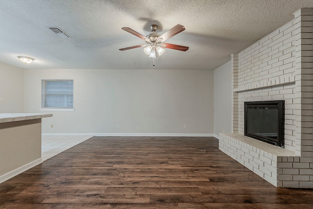1600 Lagoona Ln, Edgecliff Village, TX 76134 - unfurnished living room featuring ceiling fan, a textured ceiling, wood finished floors, a fireplace, and baseboards