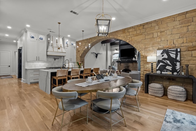 1100 La Paloma Ct, Southlake, TX 76092 - dining space featuring a chandelier, arched walkways, light wood finished floors, ornamental molding, and a fireplace