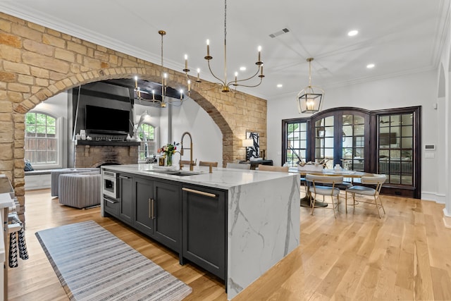 1100 La Paloma Ct, Southlake, TX 76092 - kitchen featuring a sink, open floor plan, arched walkways, ornamental molding, and light stone counters