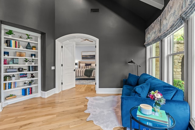 sitting room featuring high vaulted ceiling, wood finished floors, baseboards, and arched walkways