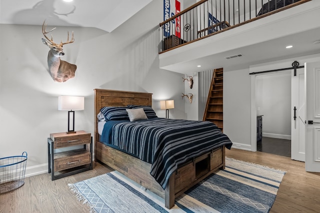 1100 La Paloma Ct, Southlake, TX 76092 - bedroom featuring a barn door, baseboards, wood finished floors, a high ceiling, and recessed lighting