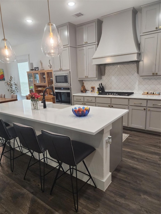 kitchen with gray cabinetry, premium range hood, stainless steel appliances, a sink, and recessed lighting