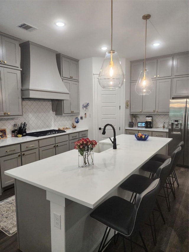 kitchen featuring premium range hood, gray cabinets, stainless steel fridge with ice dispenser, a sink, and dark wood-style floors