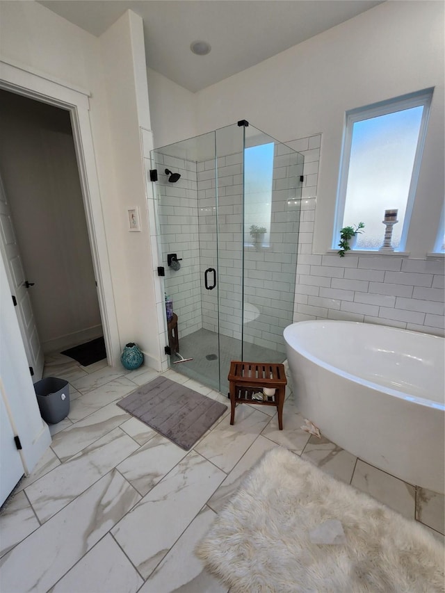 bathroom featuring a freestanding tub, a stall shower, and marble finish floors