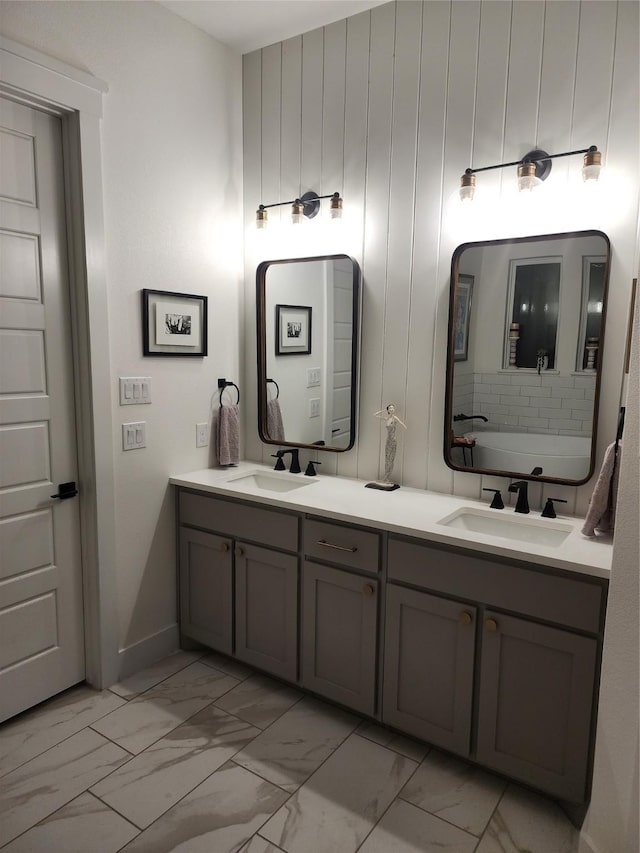 full bathroom with marble finish floors, double vanity, and baseboards