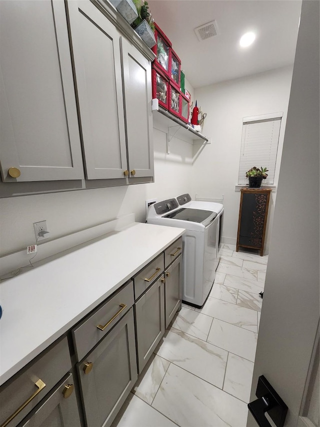 laundry area featuring independent washer and dryer, light marble finish floors, and cabinet space