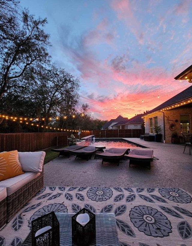 patio terrace at dusk featuring an outdoor living space with a fire pit and a fenced backyard