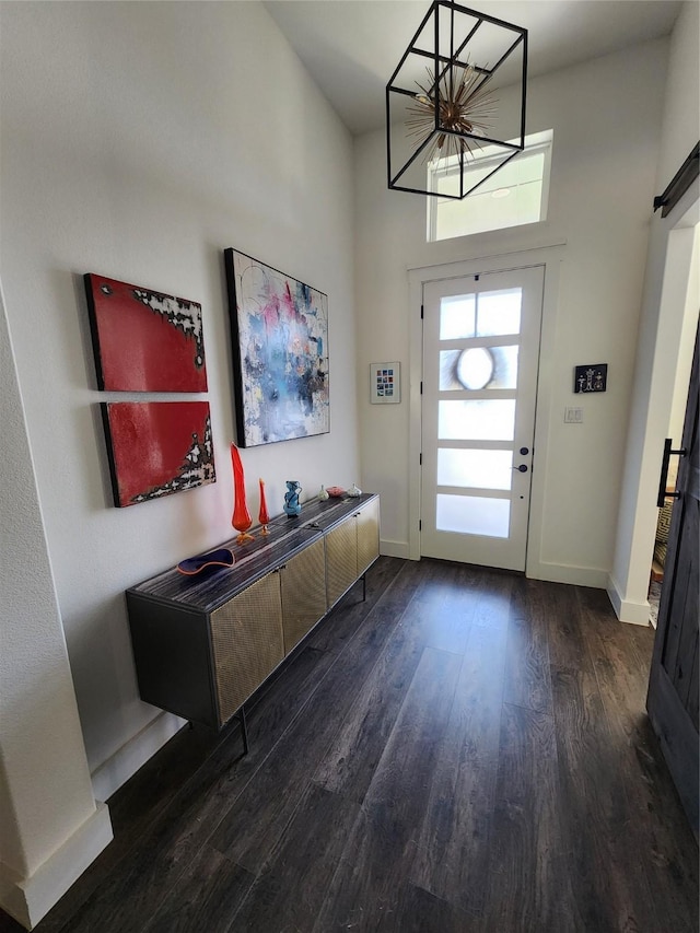 foyer entrance featuring wood finished floors, a chandelier, baseboards, and a towering ceiling