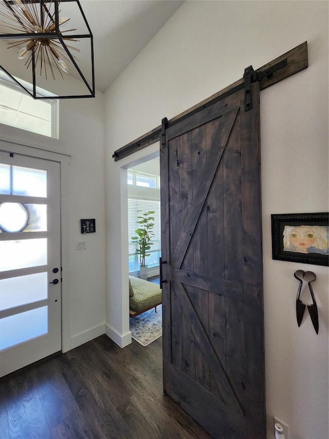 entrance foyer with a barn door, dark wood-type flooring, and baseboards