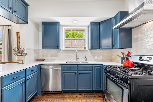 5533 Bonita Ave, Dallas, TX 75206 - kitchen featuring stainless steel appliances, a sink, blue cabinetry, wall chimney exhaust hood, and dark wood-style floors