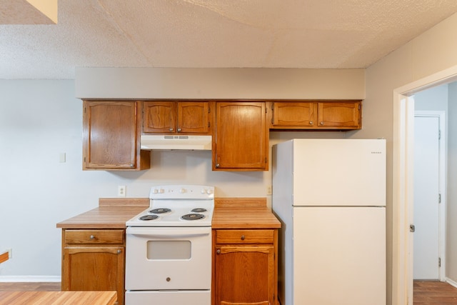 kitchen featuring white appliances, under cabinet range hood, light countertops, brown cabinets, and a textured ceiling