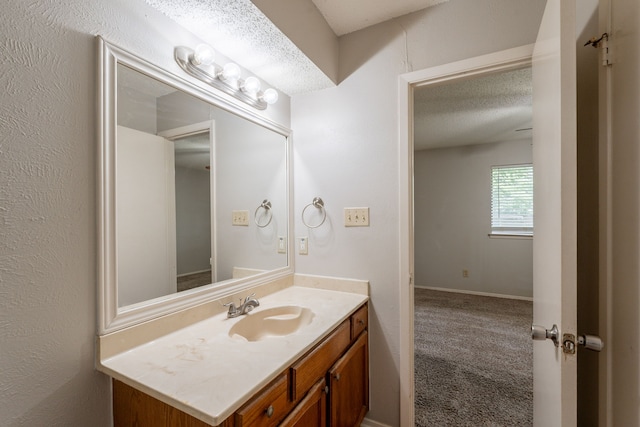 bathroom with a textured ceiling, vanity, and baseboards