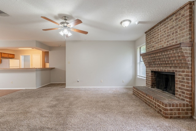 unfurnished living room with carpet floors, a textured ceiling, a brick fireplace, ceiling fan, and baseboards