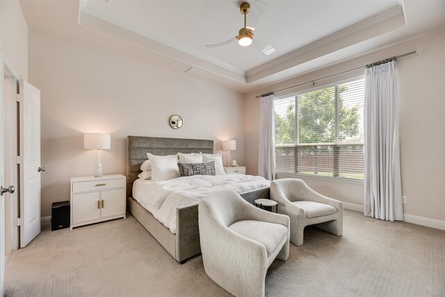 bedroom featuring a raised ceiling, crown molding, light colored carpet, baseboards, and a ceiling fan