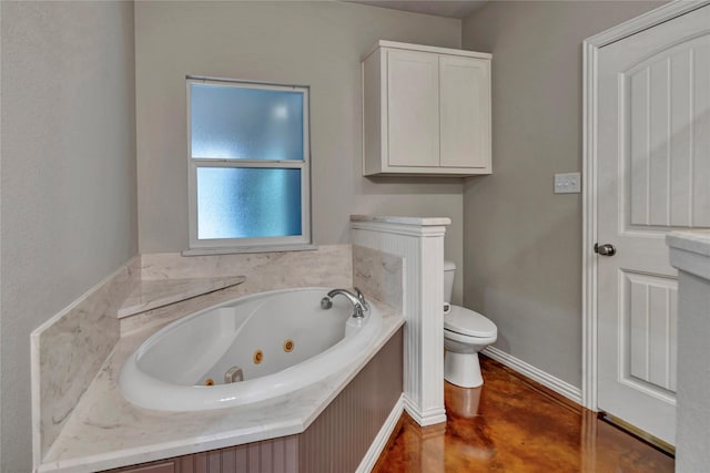 full bath featuring toilet, a jetted tub, finished concrete flooring, and baseboards