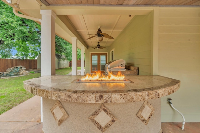 view of patio featuring a fenced backyard, ceiling fan, a fire pit, and a sink