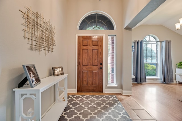 tiled foyer entrance with healthy amount of natural light, vaulted ceiling, and baseboards