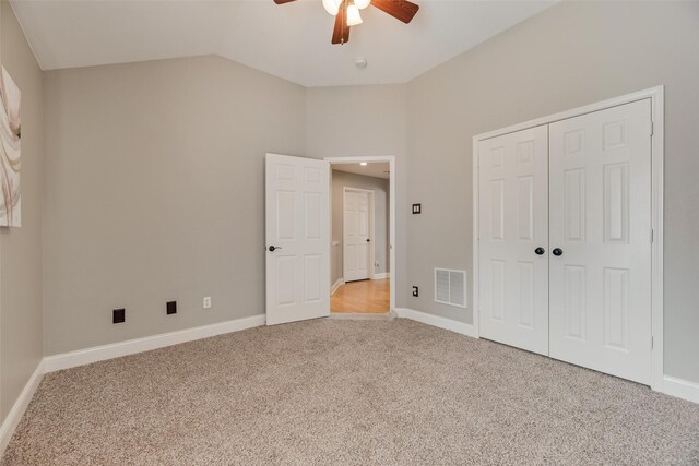 unfurnished bedroom featuring lofted ceiling, carpet, baseboards, and a closet