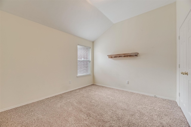 carpeted empty room featuring lofted ceiling and baseboards