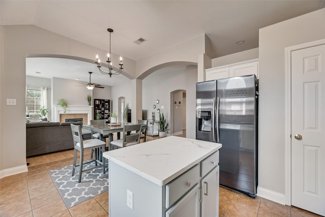 kitchen featuring stainless steel fridge, a ceiling fan, arched walkways, light tile patterned flooring, and a kitchen island