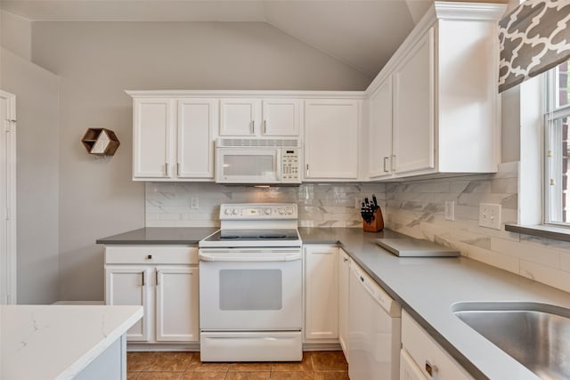 kitchen featuring white appliances, lofted ceiling, white cabinets, decorative backsplash, and light tile patterned floors