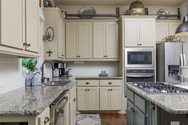 kitchen with stainless steel appliances, a sink, light stone countertops, and backsplash