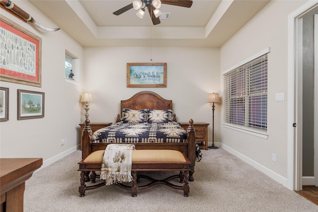 bedroom with a raised ceiling, carpet floors, ceiling fan, and baseboards
