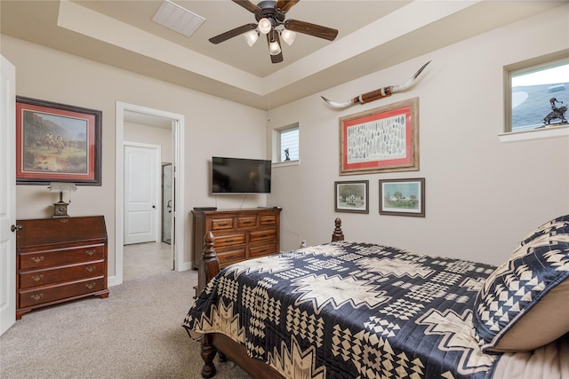bedroom featuring carpet, a raised ceiling, and a ceiling fan
