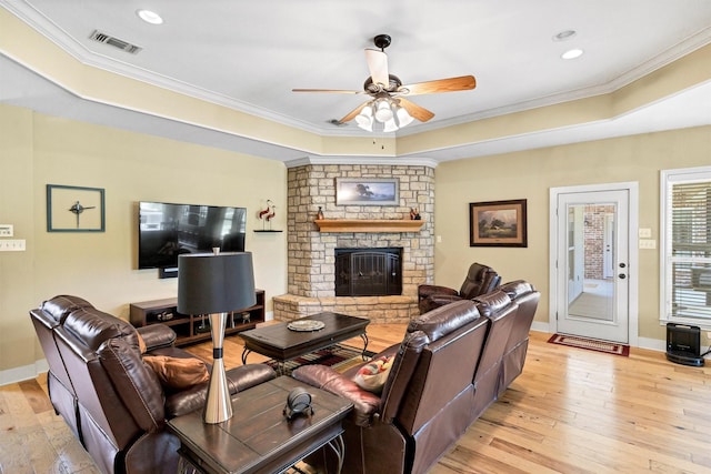 3568 Green Meadows Dr, Glen Rose, TX 76043 - living room featuring light wood-type flooring, a ceiling fan, a stone fireplace, crown molding, and a raised ceiling