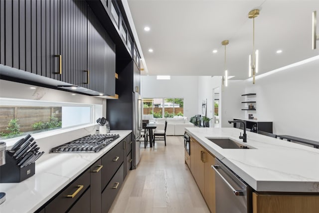 kitchen featuring stainless steel appliances, a sink, open floor plan, modern cabinets, and a large island