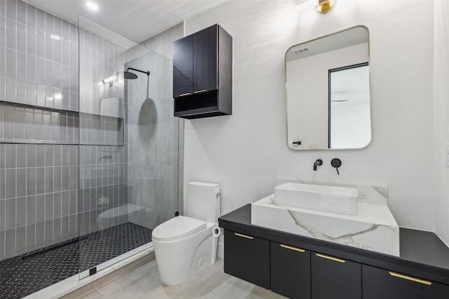 bathroom featuring a walk in shower, toilet, and vanity