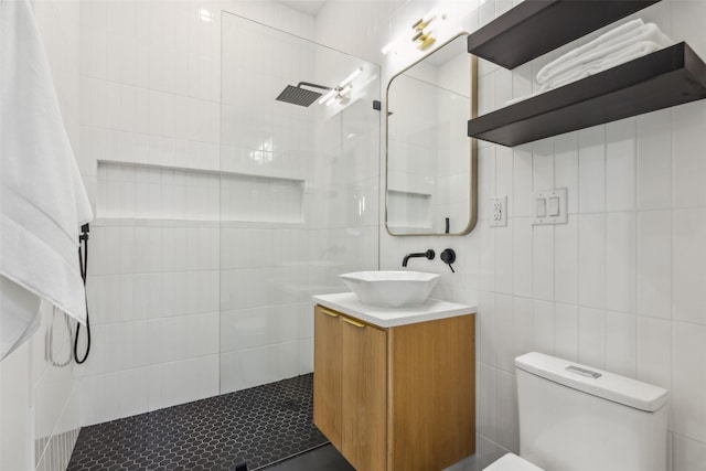 bathroom featuring tile walls, walk in shower, toilet, and vanity