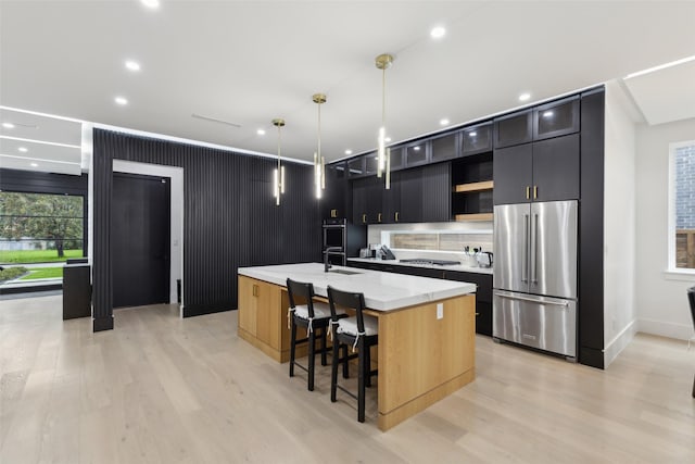 kitchen featuring high quality fridge, open shelves, a kitchen island with sink, gas stovetop, and a sink