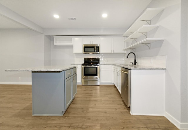 14590 Coffee Ln, Scurry, TX 75158 - kitchen featuring stainless steel appliances, open shelves, white cabinets, light wood-type flooring, and a center island