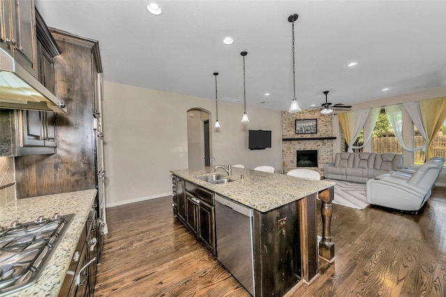 5112 Fringetree Dr, Mckinney, TX 75071 - kitchen featuring ceiling fan, dark wood-type flooring, a brick fireplace, arched walkways, and light stone countertops