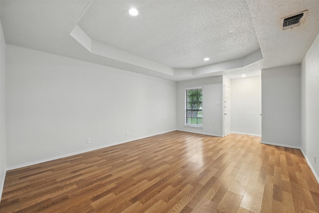 6708 S Creek Dr, Fort Worth, TX 76133 - unfurnished room with light wood finished floors, a textured ceiling, a tray ceiling, baseboards, and recessed lighting