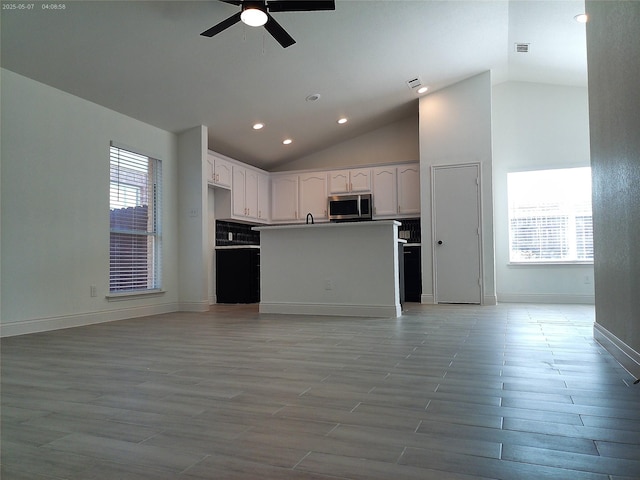 6025 Melanie Dr, Fort Worth, TX 76131 - kitchen with stainless steel microwave, open floor plan, lofted ceiling, a ceiling fan, and white cabinets