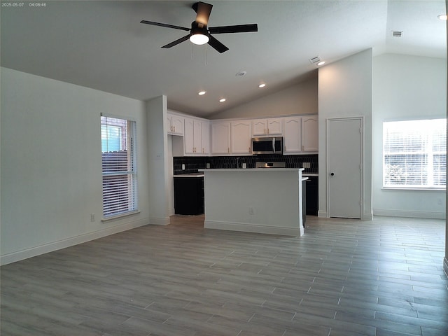 6025 Melanie Dr, Fort Worth, TX 76131 - kitchen featuring stainless steel microwave, vaulted ceiling, white cabinetry, ceiling fan, and open floor plan
