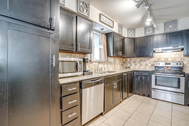 3554 Cromart Ct N, Fort Worth, TX 76133 - kitchen with appliances with stainless steel finishes, under cabinet range hood, a sink, light tile patterned flooring, and decorative backsplash